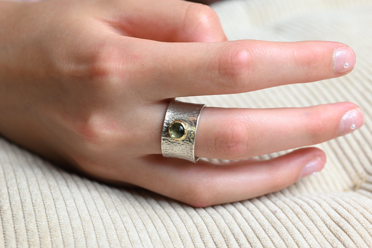 13 mm breiter Bicolor-Ring aus Silber und Gold mit grünem Peridot, getragen an einer Hand.