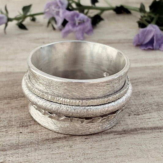 Damenring aus 925 Silber, ca. 13 mm breit, mit matt gekratzter Oberfläche und drei Drehringen.